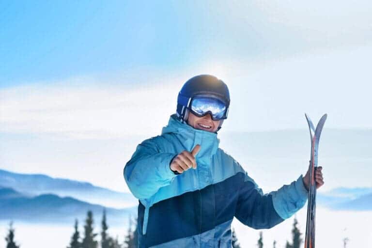 Meneer is aan het skieen en heeft een skiduim en steekt zijn duim op